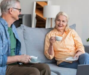 Senior woman enjoying the comfort of friends having tea as she ages at home. Promyse Home Care is there to offer additional assistance when needed.