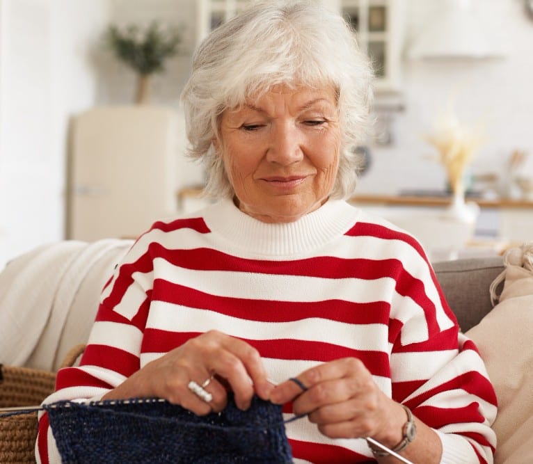 Senior loved one knitting a blanket to give back to a local shelter.