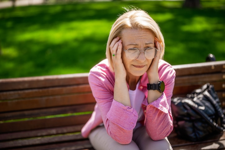 Older woman suffering from ringing in her ears commonly known as Tinnitus.