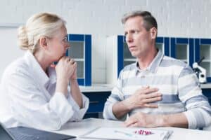 Man is discussing with the nurse the symptoms and warning signs of having a heart attack.