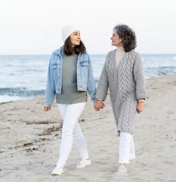 Mother with Dementia walking with teenage daughter on the beach