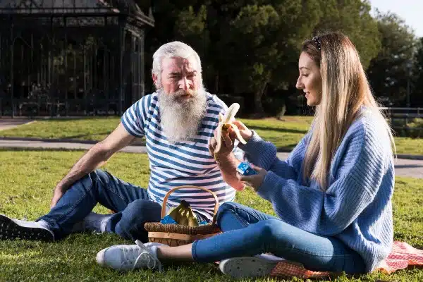 A young woman is enjoying the company of her grandfather in the park.